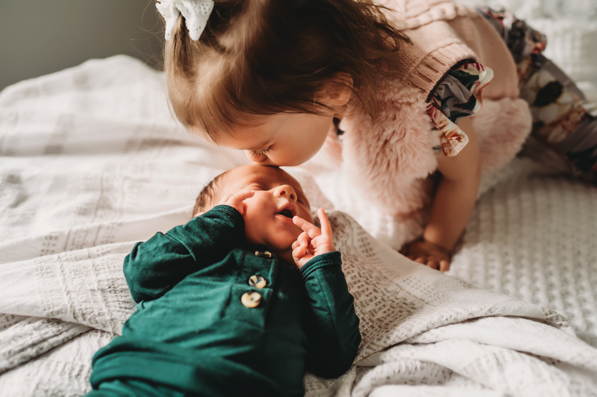 Big sister kisses baby newborn photoshoot.jpg