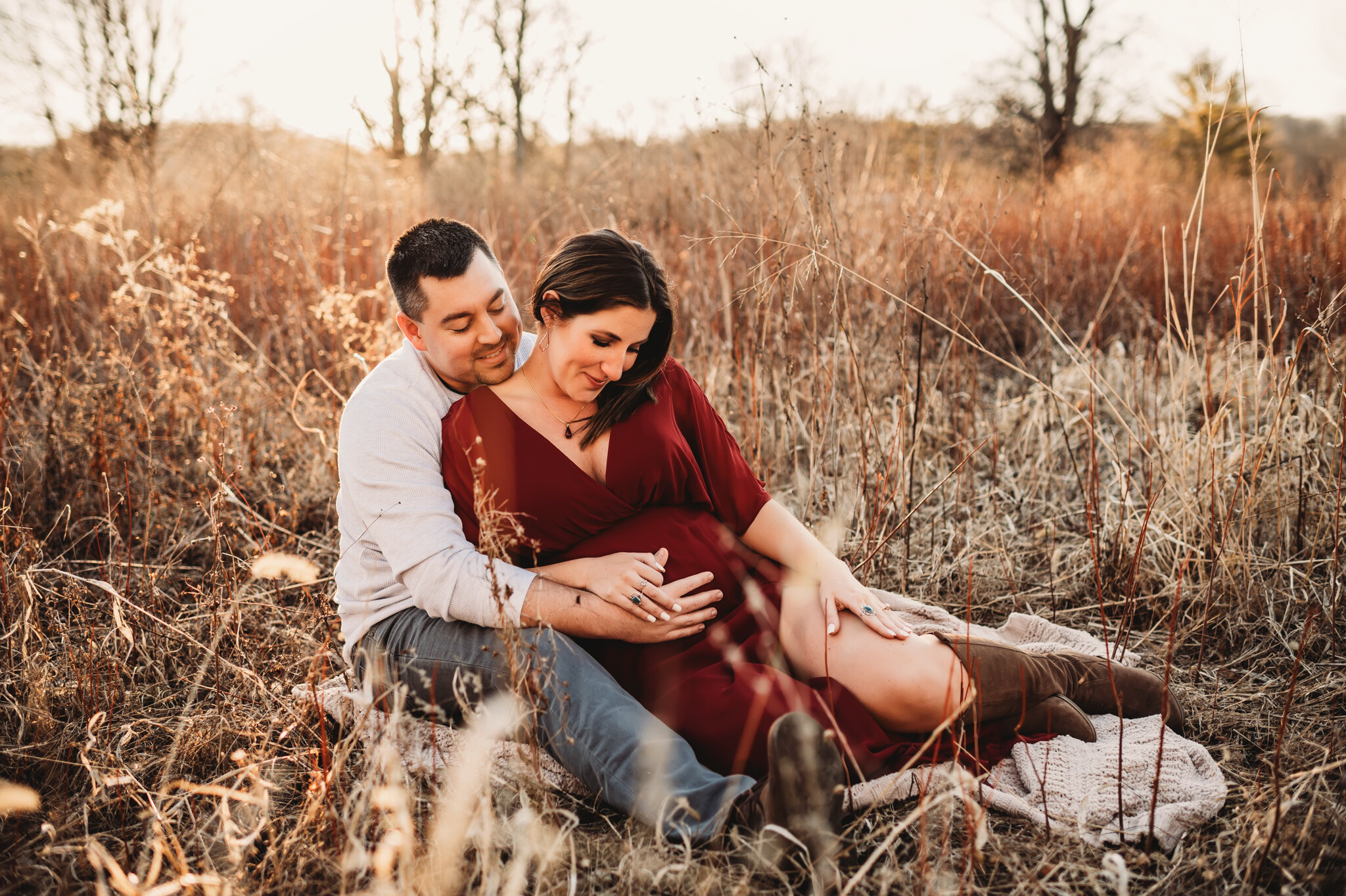 central illinois family photographer, couple sits in grass looking at baby bump
