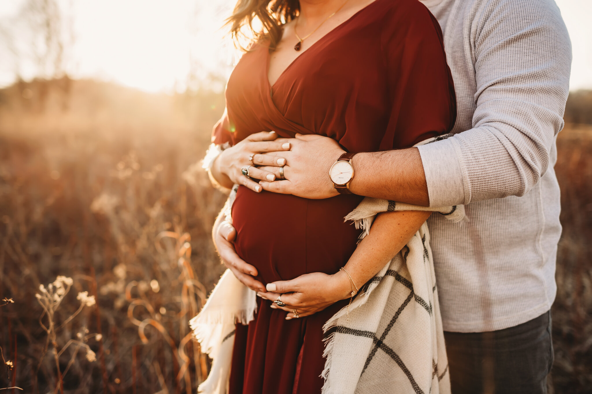 Peoria IL maternity photos, couple stands with sunset holding pregnant belly