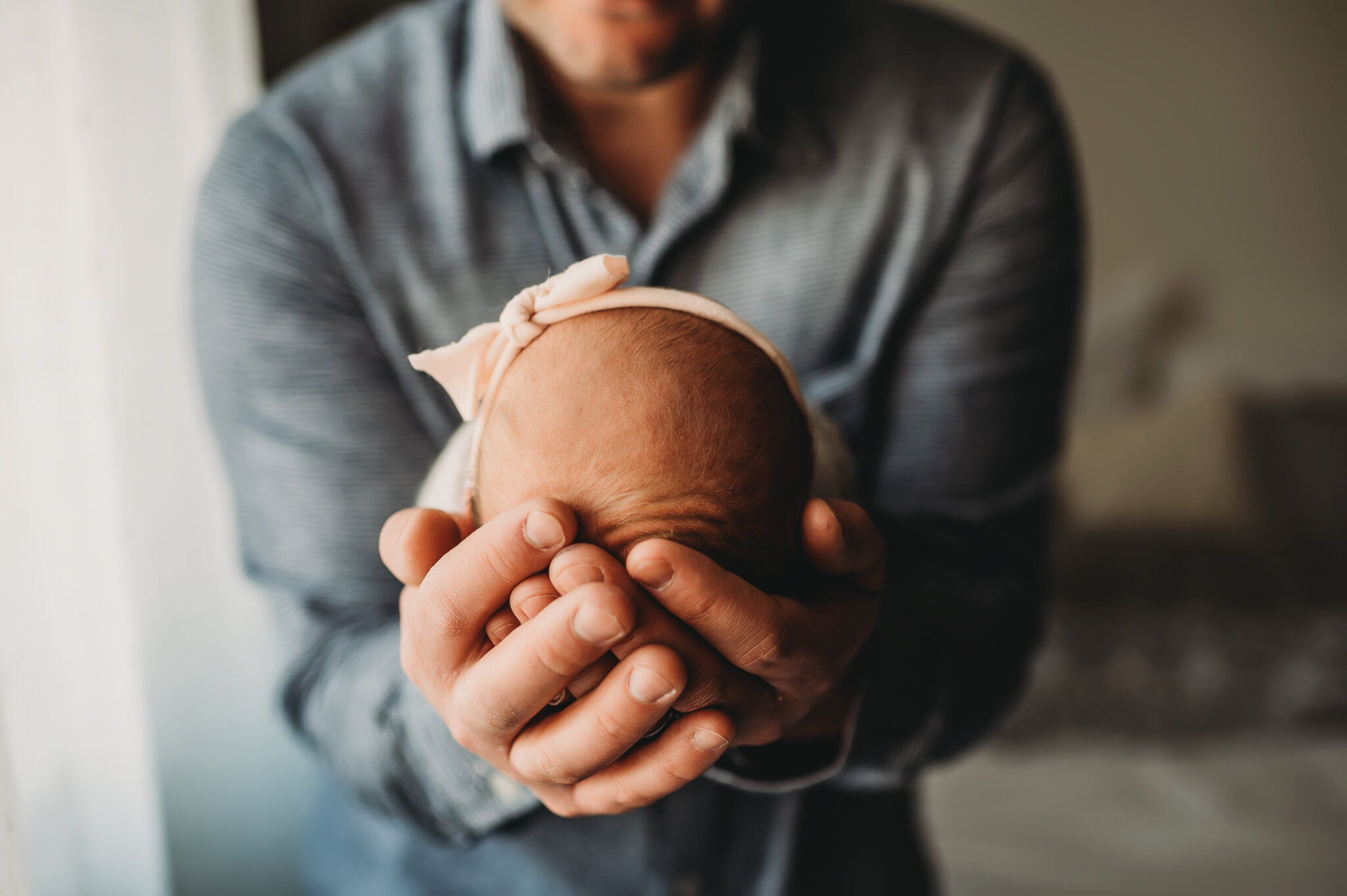 Newborn session dad holds baby's head in hands.jpg