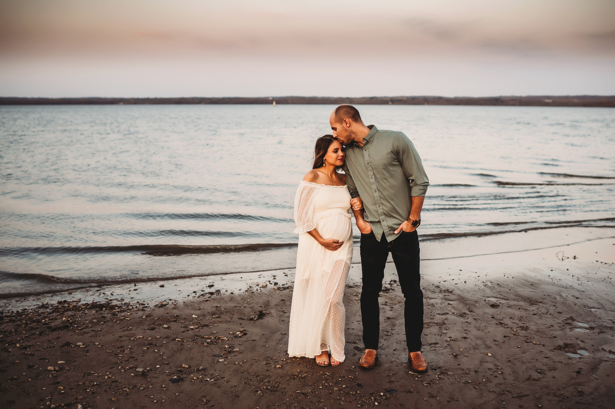 couple stands near water maternity photos.jpg