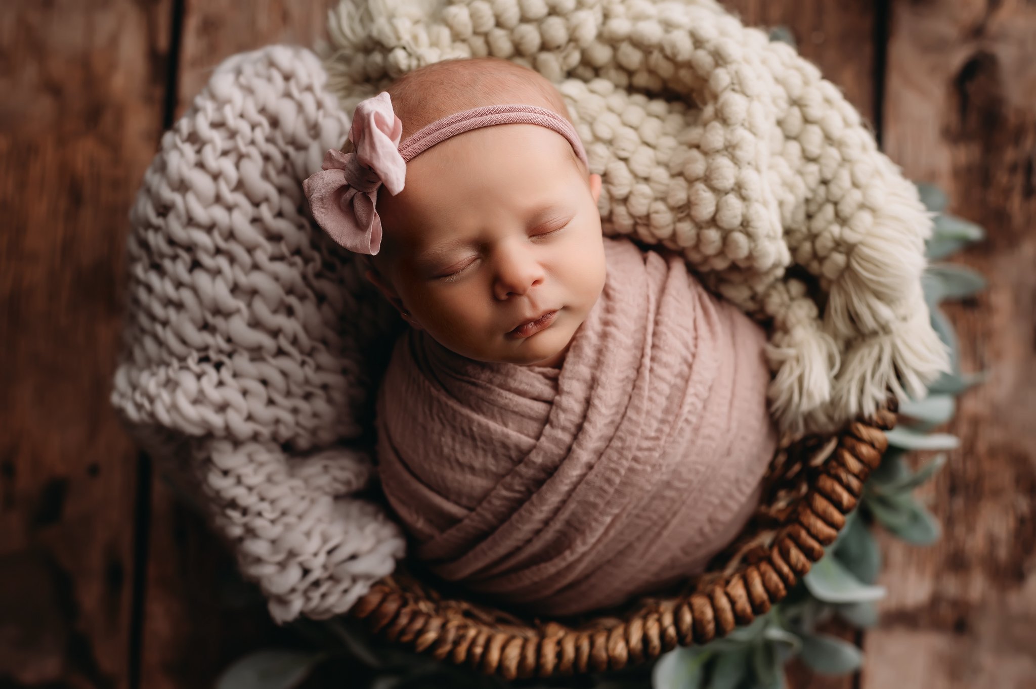 Newborn with bow lays in basket.jpg