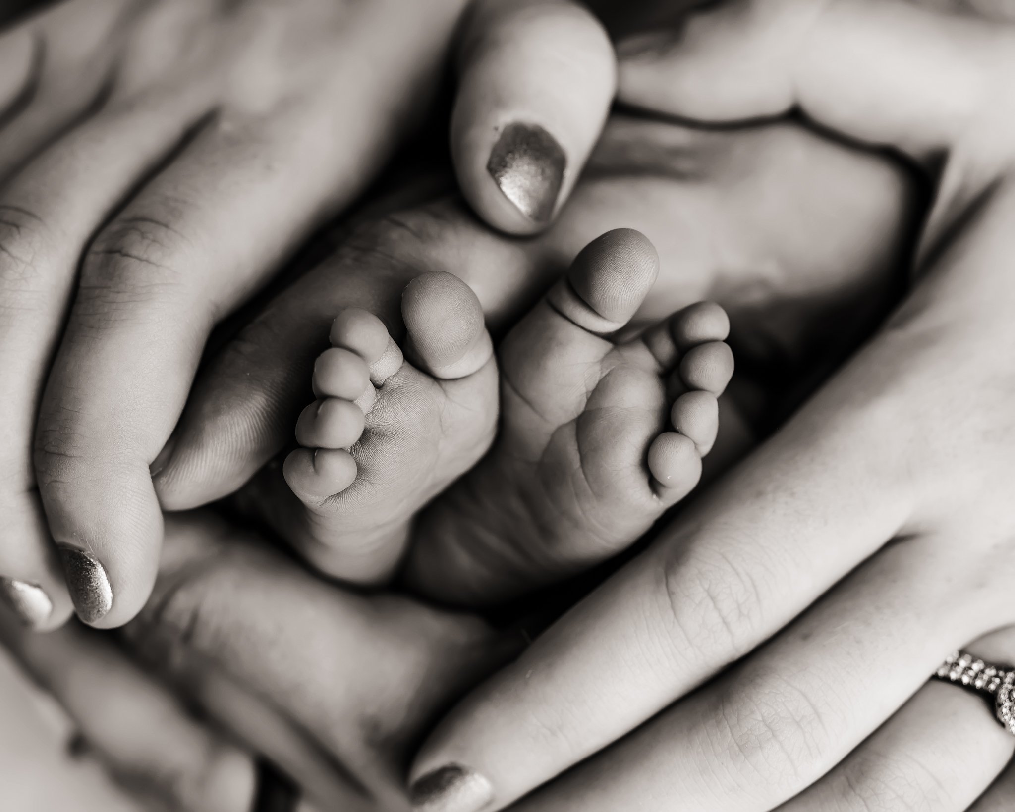 Parents wrap hands around baby toes.jpg