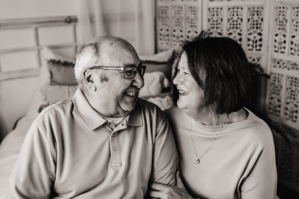 Black and white photo of grandma and grandpa laughing and smiling at each other
