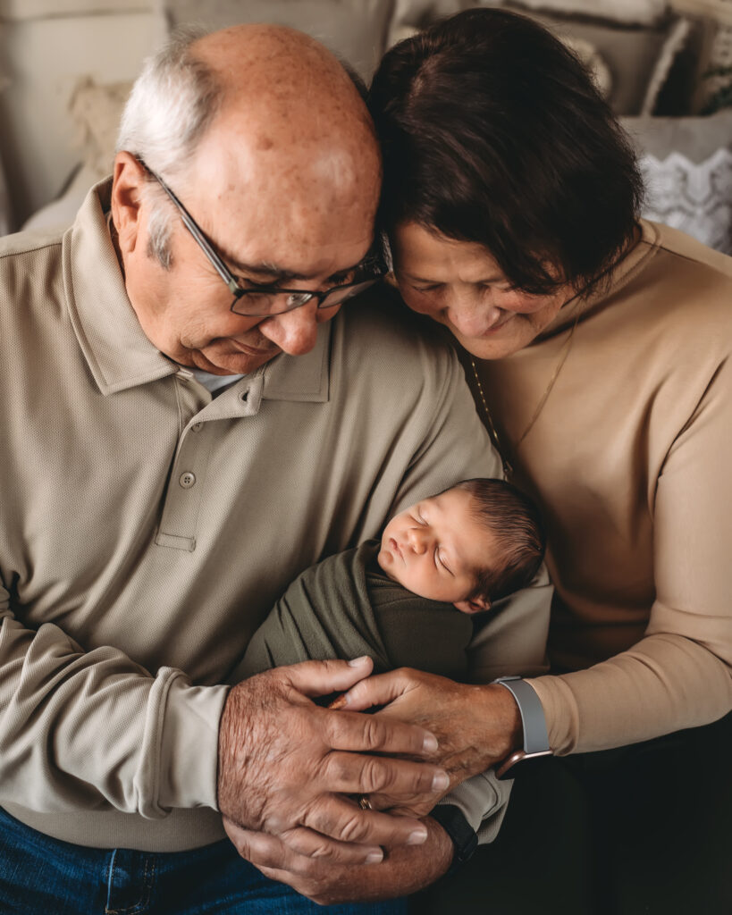 grandparents hold newborn grandson