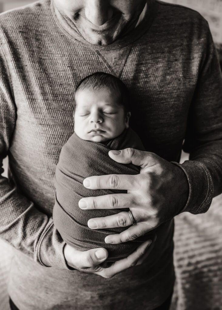 dad holds newborn son black and white photo