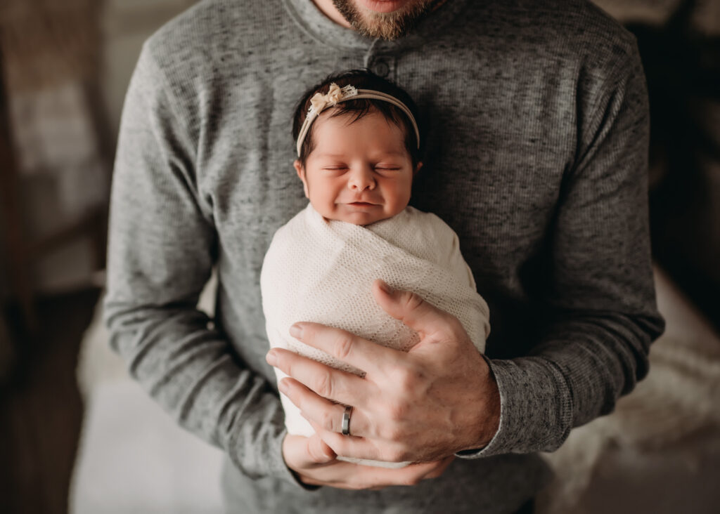 Dad holds baby girl with cream wrap and nude colored bow