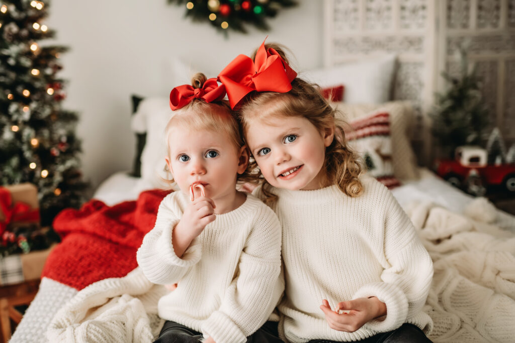 sisters sit together wearing big red bows