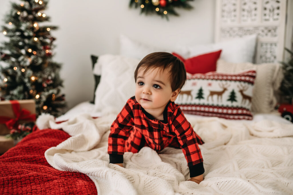 Little boy crawls on Christmas bed in Jammies
