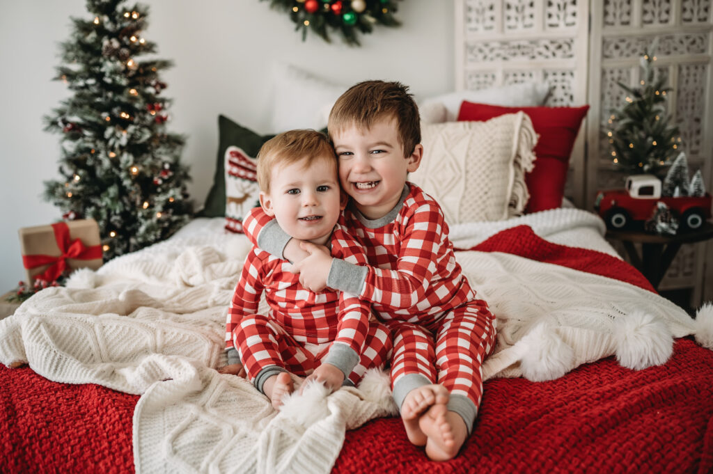 Christmas Minis two boys sit together on bed in PJs