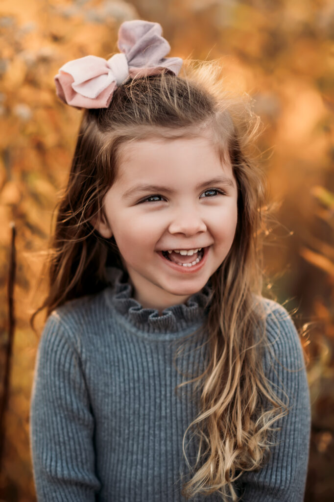 little girl with bow laughs while looking off camera