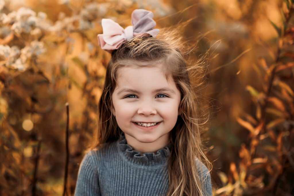headshot of little girl with pink bow and grey dress