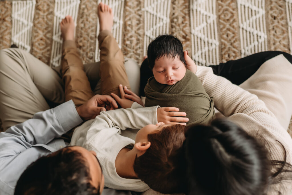 family looks down together at newborn baby