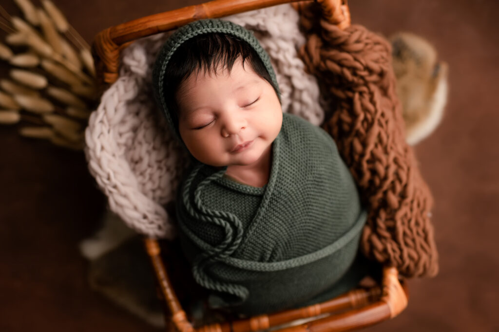 newborn baby smiles in green knit swaddle