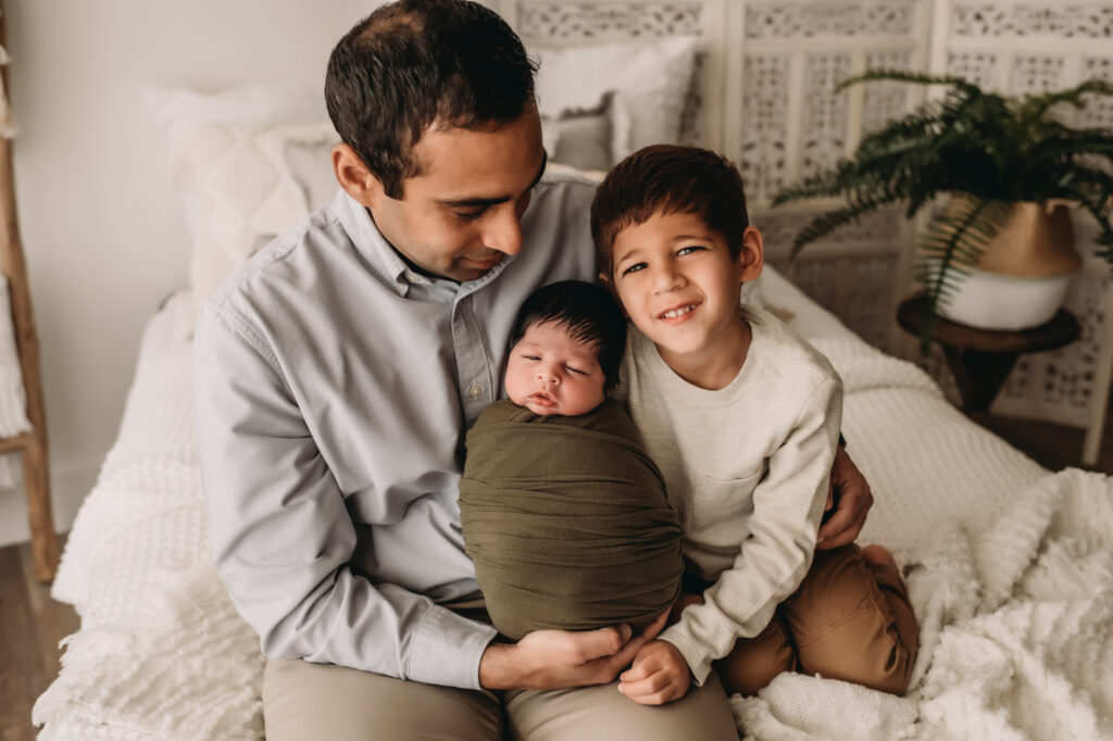 dad, brother and newborn pose together