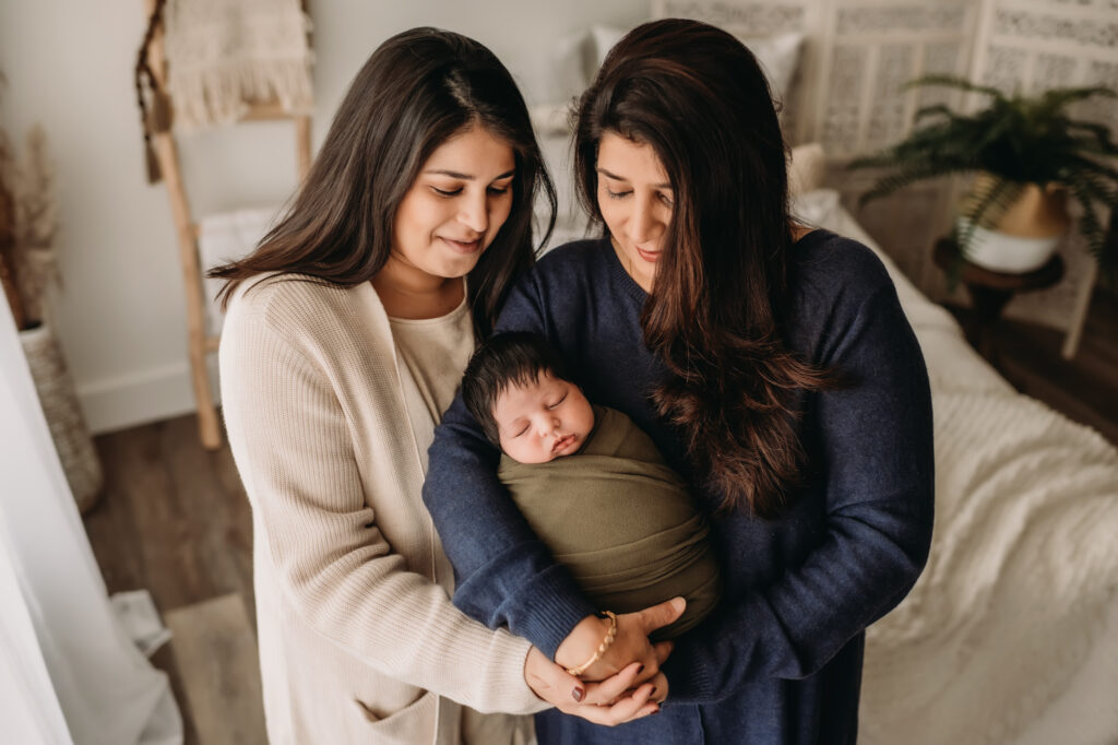 mom, daughter and newborn baby pose together